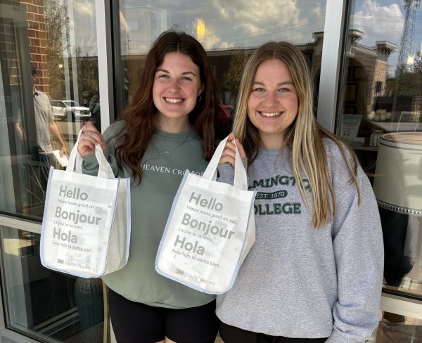 Two girls holding up white bags that say "Hello, Bonjour, Hola" 