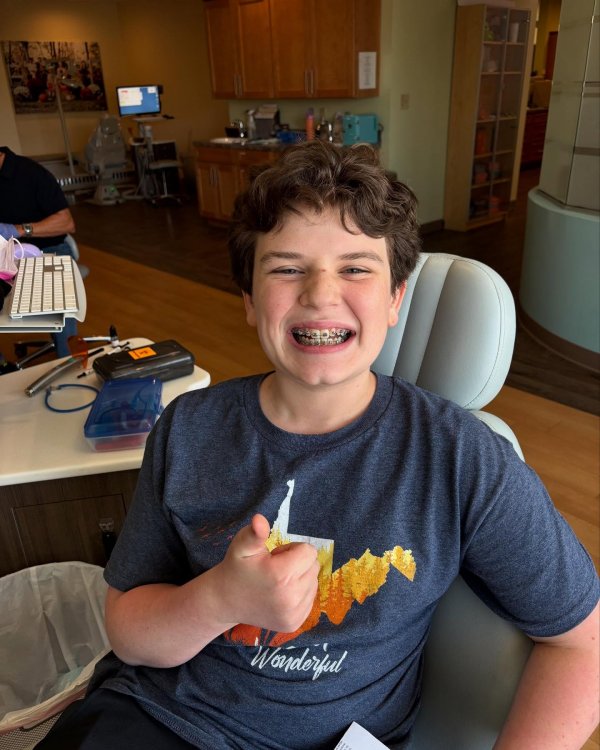 Boy smiling and thumb up after receiving a new set of braces 