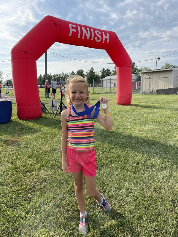 Little girl holding up medal after a race