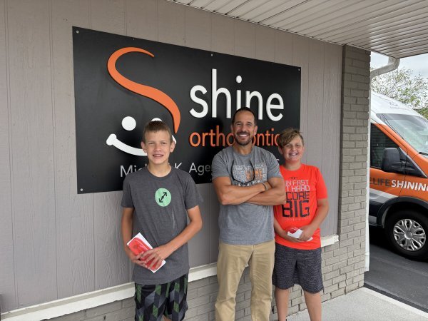 Dr Mike poses with two boys outside the Shine building
